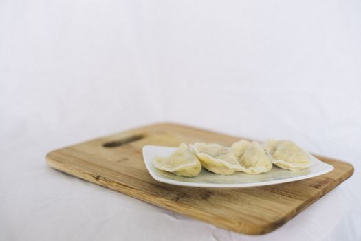 Close-up of appetizing dumplings on a plate over a wooden cutting board.