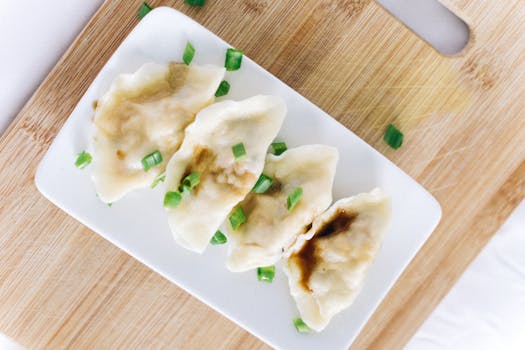 Tasty Chinese dumplings garnished with green onions on a wooden board.