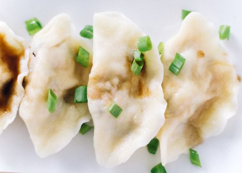 Free Appetizing close-up of Chinese dumplings garnished with fresh scallions on a white plate. Stock Photo