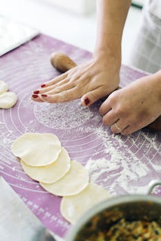 Close-up of hands rolling dough on a mat, perfect for food preparation visuals.