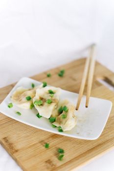 Close-up of appetizing Chinese dumplings garnished with green onions.