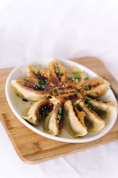 Free Crispy and golden dumplings arranged in a circle, garnished with green onions and sesame seeds. Stock Photo