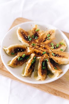 Delicious crispy fried dumplings garnished with green onions on a white plate.