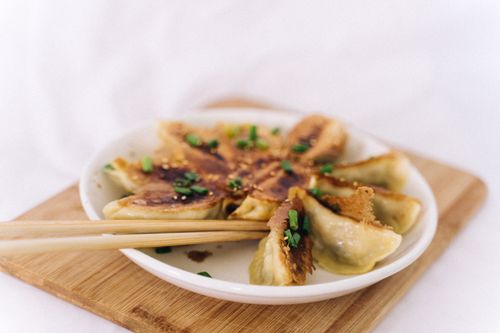 Free Close-up of delicious pan-fried dumplings with green onions on a plate, served with chopsticks. Stock Photo