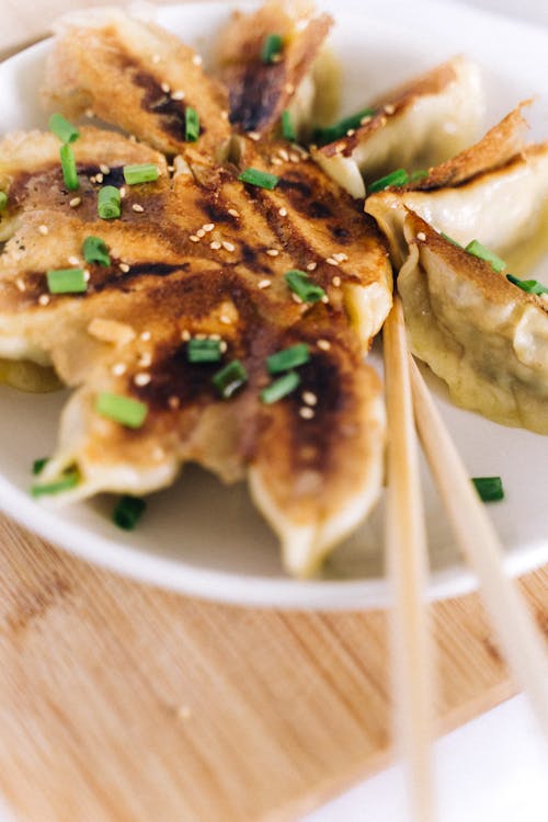 Free Crispy Dumplings on a Ceramic Plate garnished with Chives Stock Photo