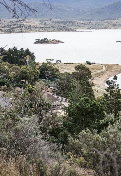 Free Rural buildings among trees with green foliage growing on shore of pond surrounded by hills Stock Photo