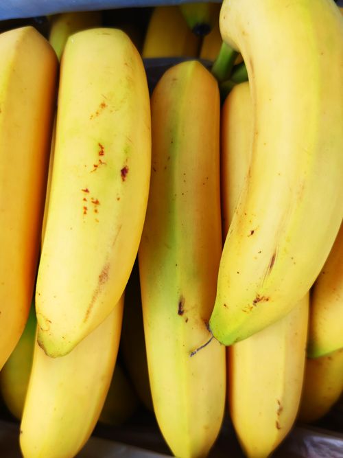Free A vibrant close-up of fresh ripe bananas stacked in a vertical arrangement, showcasing their bright yellow color. Stock Photo
