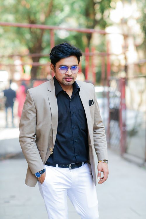Free Trendy man with sunglasses and blazer walking outdoors, showcasing modern fashion in Mumbai. Stock Photo