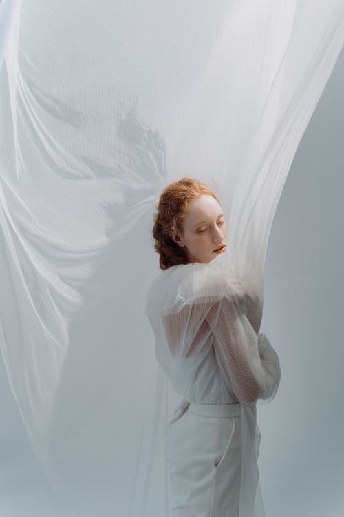 Free Elegant portrait of a woman with ginger hair in sheer fabric, evoking a dreamy and ethereal mood. Stock Photo