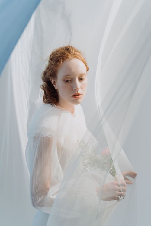 Free A stunning portrait of a red-haired bride enveloped in a flowing white veil, exuding elegance and sophistication. Stock Photo