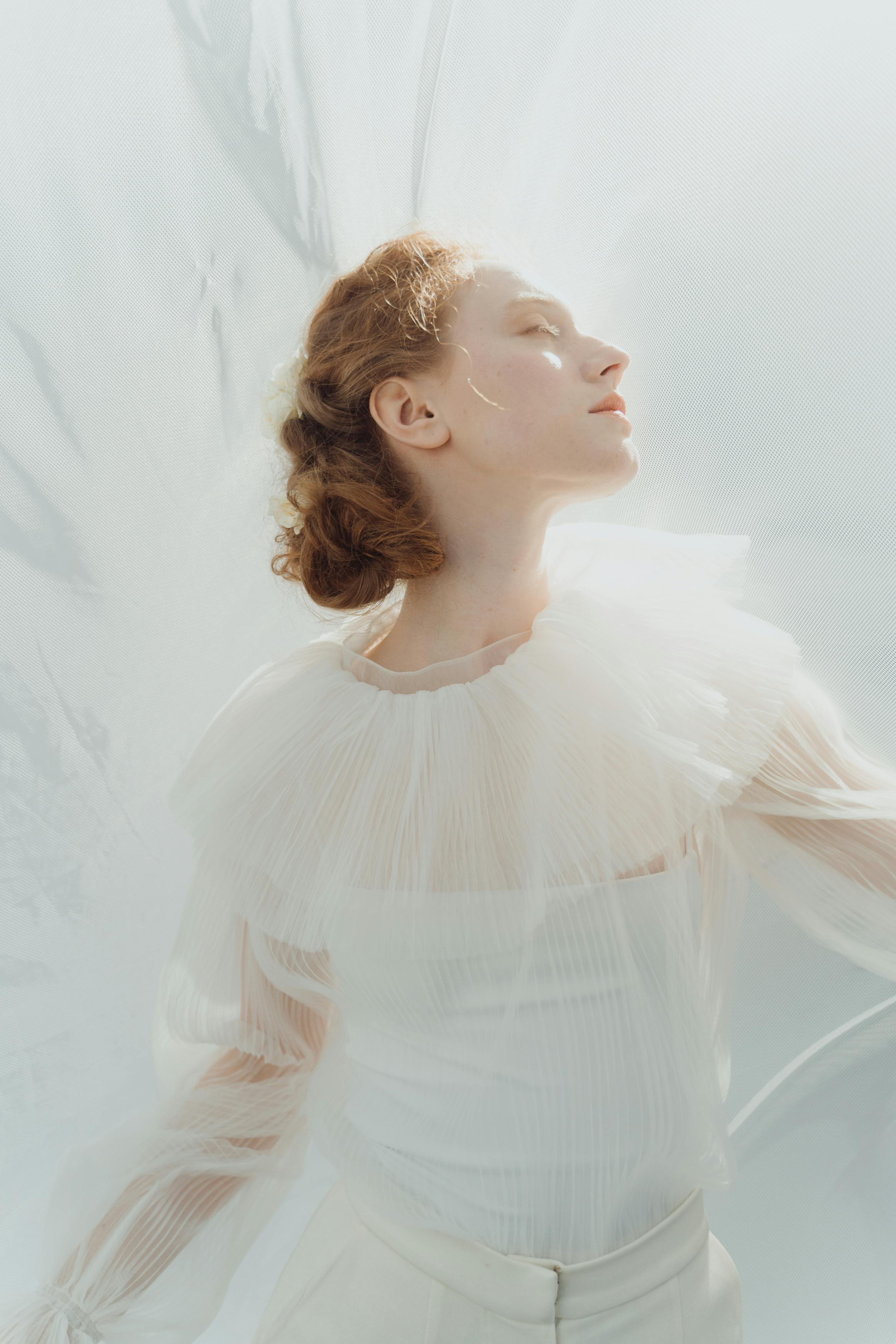 Free A Woman in White Long Sleeves with Her Eyes Closed Stock Photo