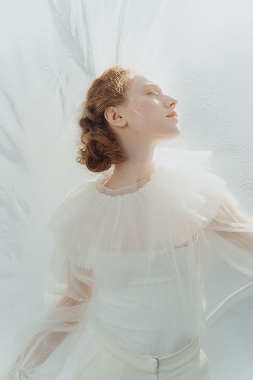 Free Graceful portrait of a woman in a sheer white top, exuding elegance and serenity. Stock Photo