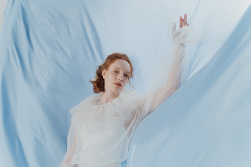 Woman in White Long Sleeve Top Standing By the Hanging Cloth