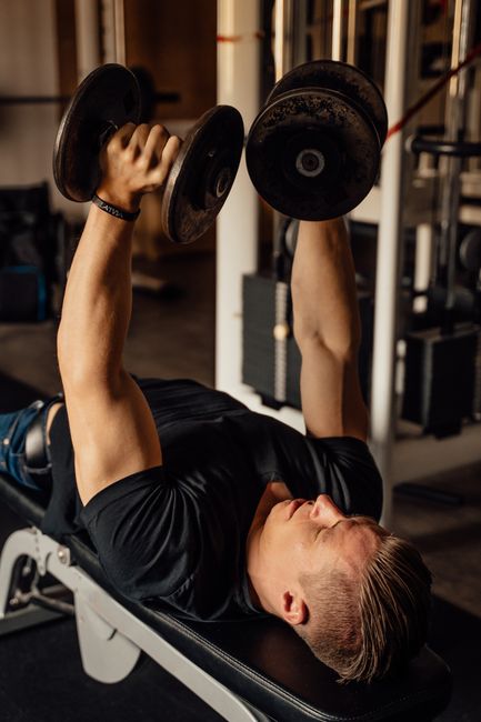 Pratiquant réalisant un mouvement avec haltères allongé sur un banc de musculation