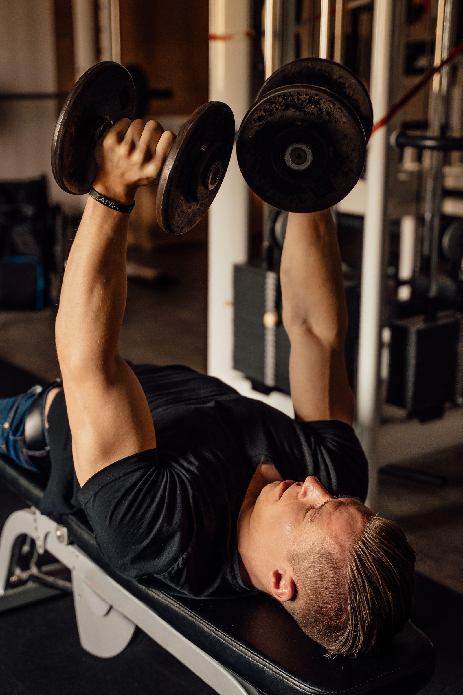 Athlete performing a dumbbell bench exercise in a gym