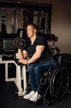 Man in a wheelchair performing dumbbell curls in a gym setting, showcasing strength and determination.
