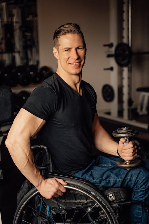 A Man Sitting on a Wheelchair while Holding a Dumbbell