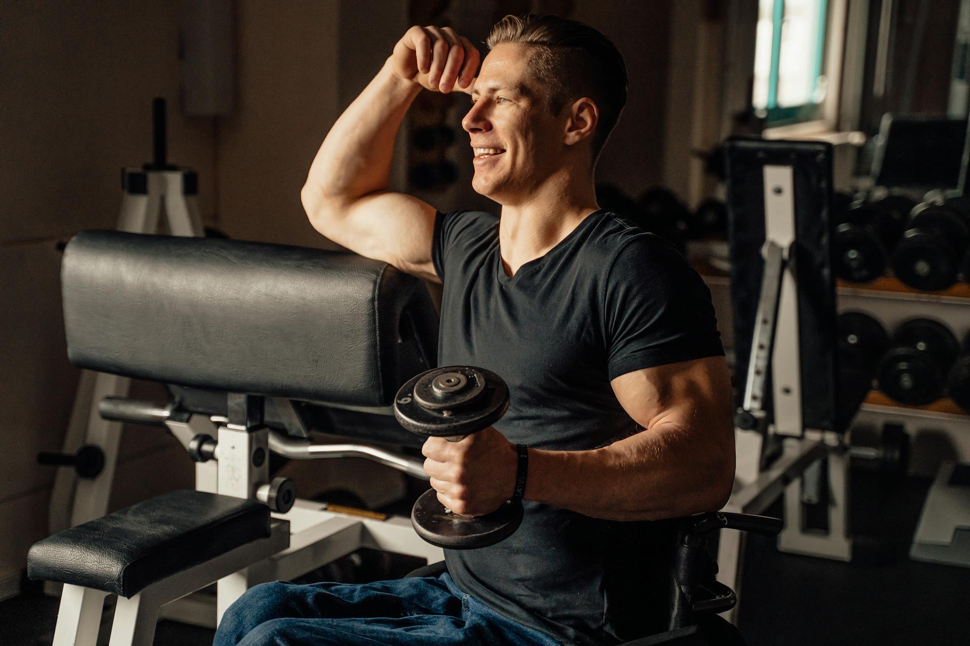 A man in a wheelchair lifting a dumbbell in a gym setting, showcasing strength and determination.