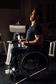 A determined man in a wheelchair exercising in a gym, showcasing strength and resilience.