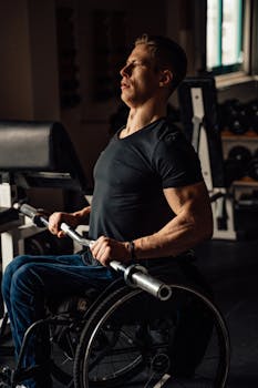 Caucasian man in wheelchair lifting weights in a gym setting.