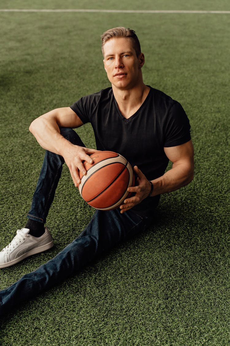 Man Holding A Ball While Sitting On The Ground