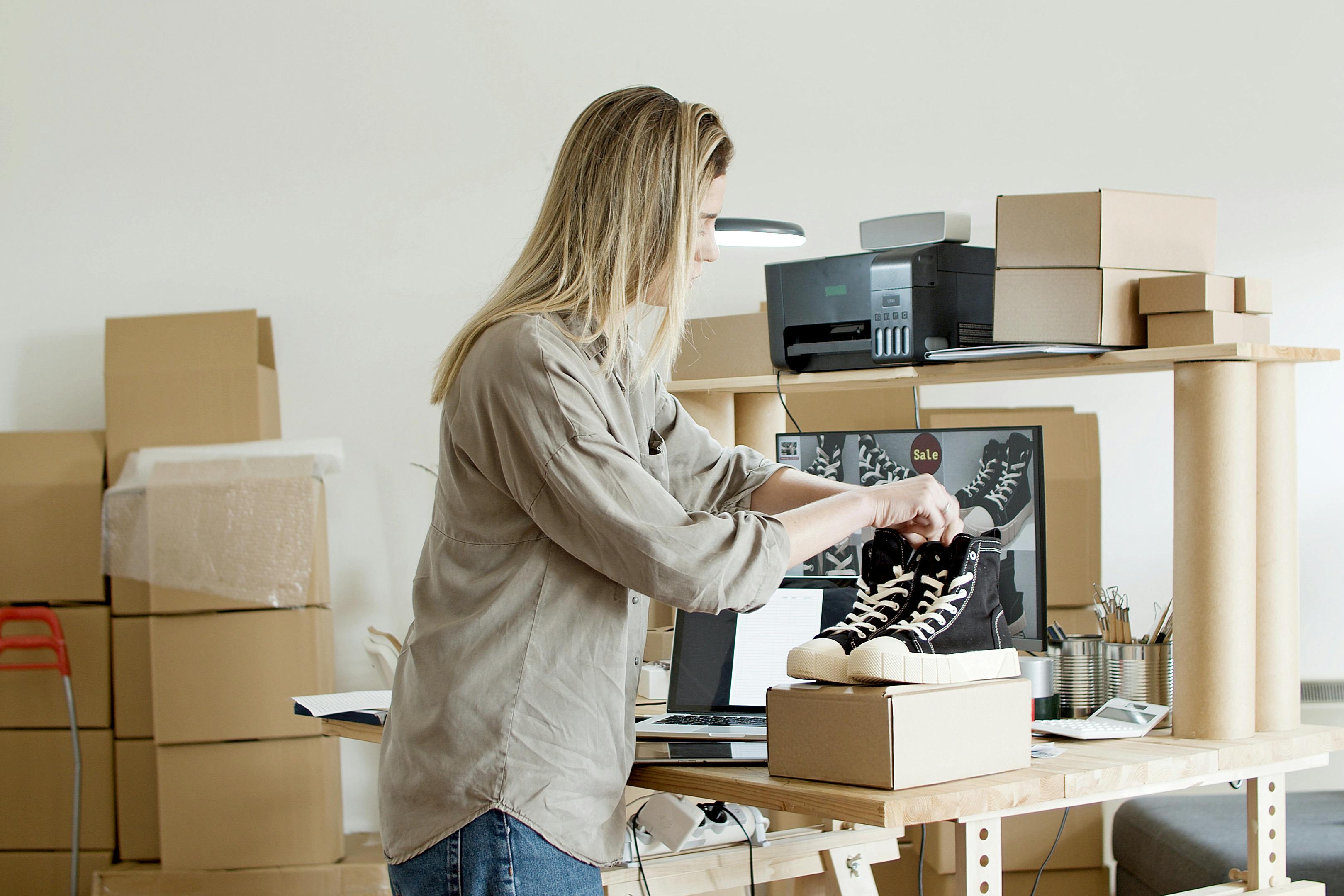 woman holding black shoes on top of the box