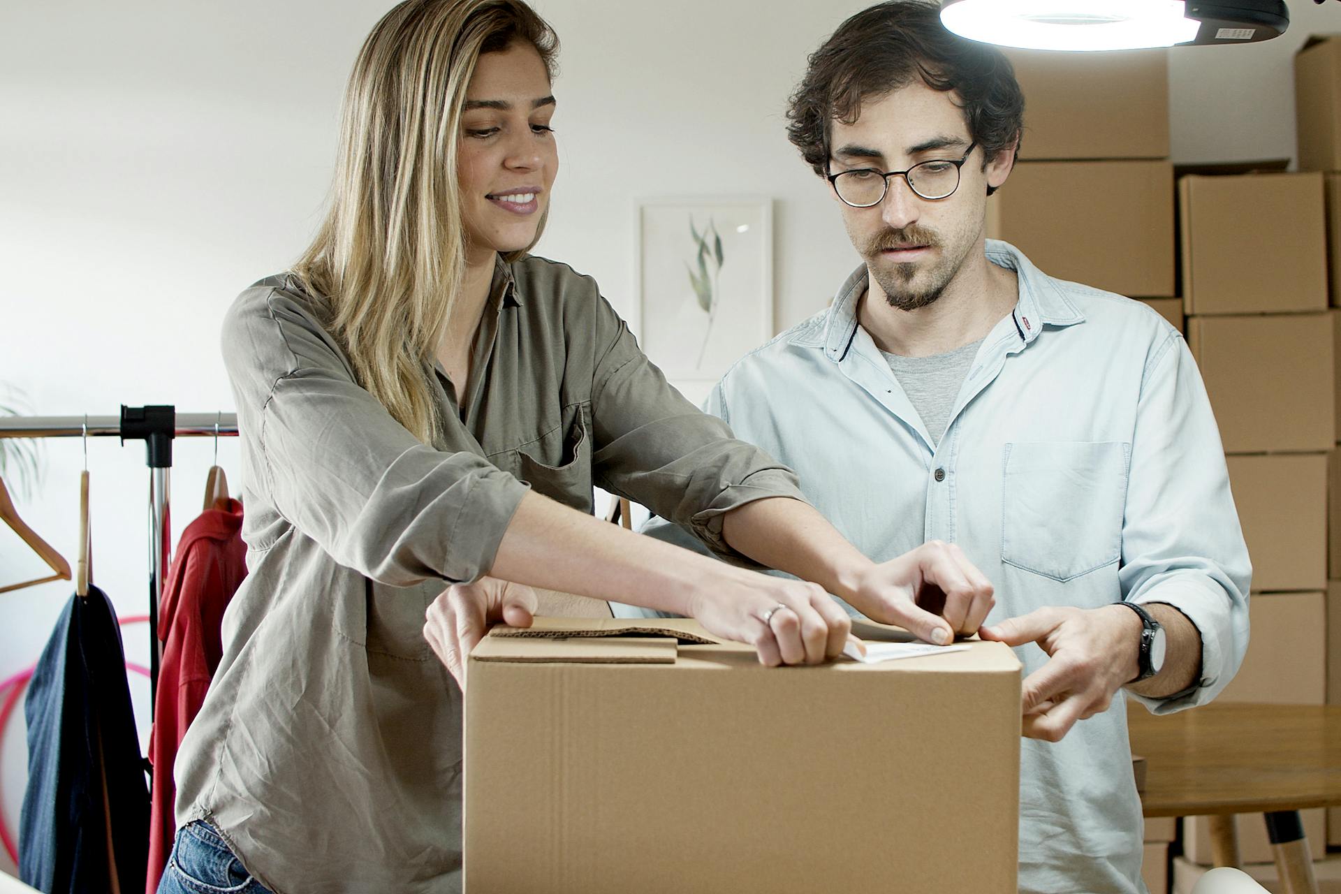 A young man and woman pack boxes in a modern office environment, symbolizing a startup business.