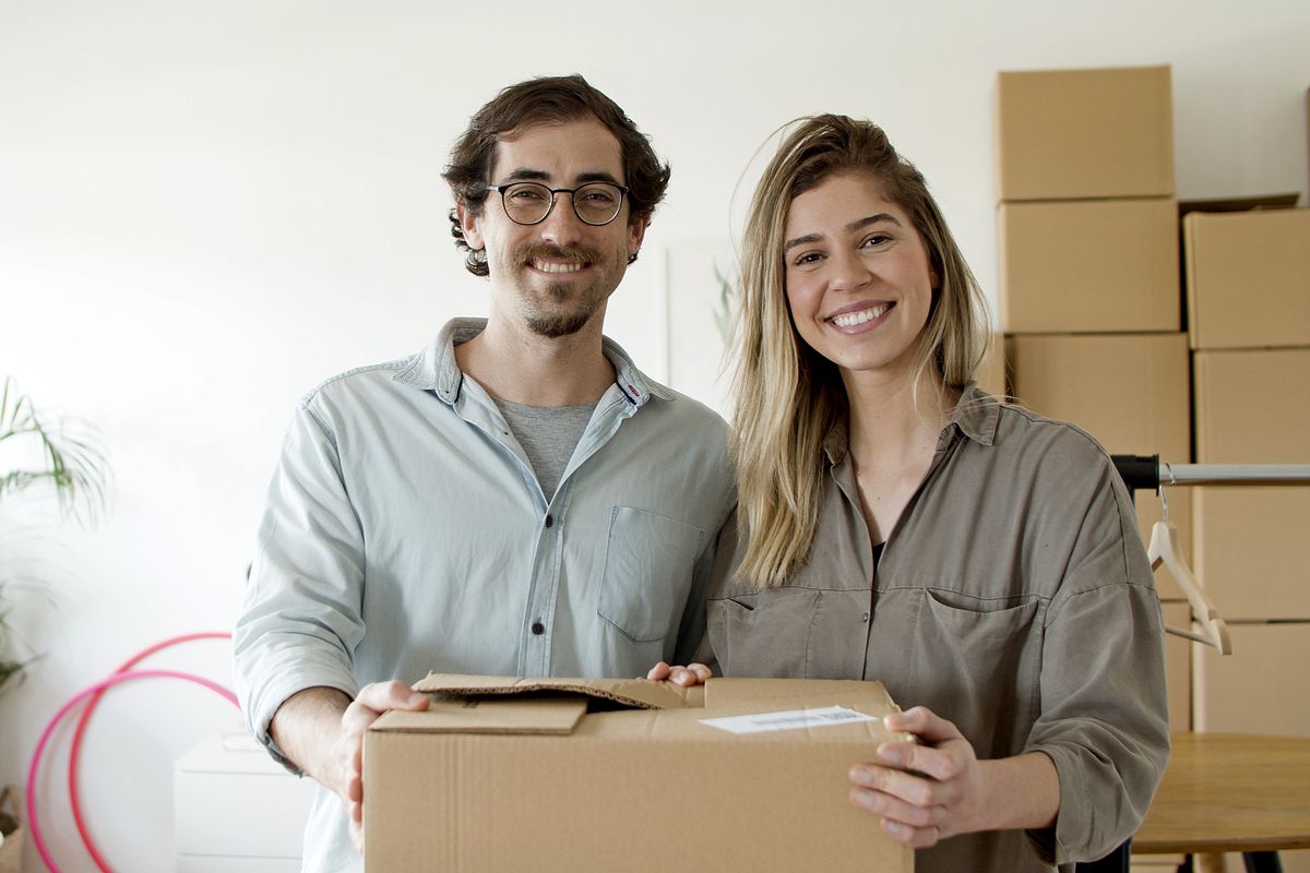 Happy male and female small business owners handling a parcel together in their store, illustrative e-commerce scenario
