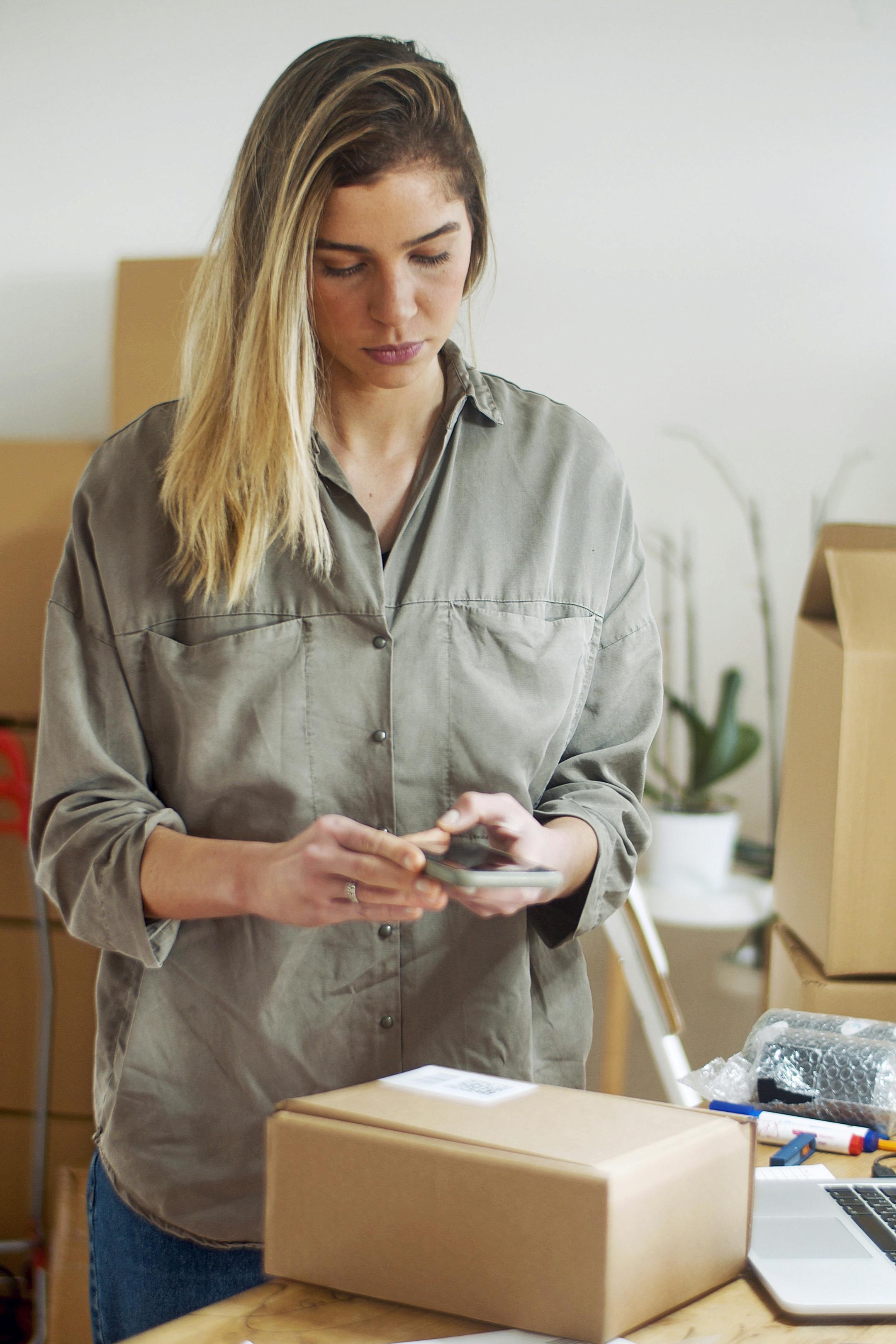 woman in gray button up long sleeve shirt holding smartphone