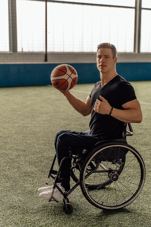 Free Man Sitting on Wheelchair while Holding a Ball Stock Photo