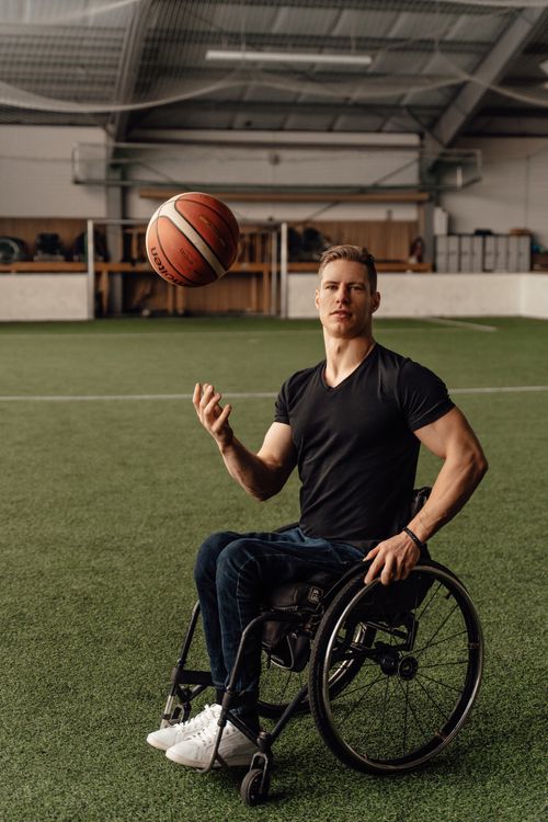 Free A determined young man in a wheelchair playing basketball indoors, showcasing strength and skill. Stock Photo
