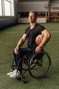 Man in Black Tank Top and Blue Denim Jeans Sitting on Black Wheelchair Holding Basketball