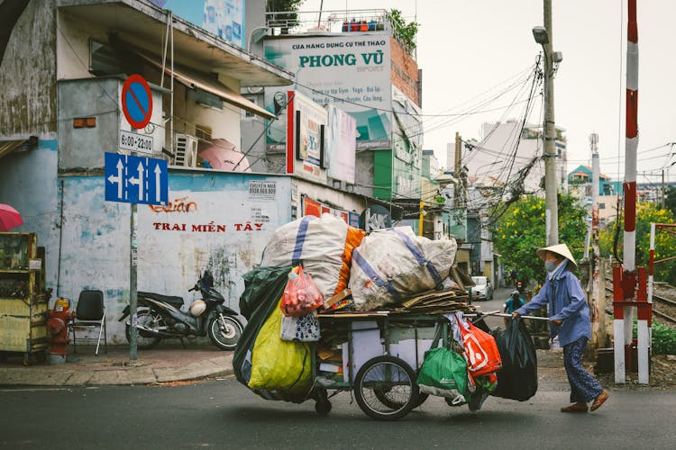 A Person Pushing A Cart Outside The Street