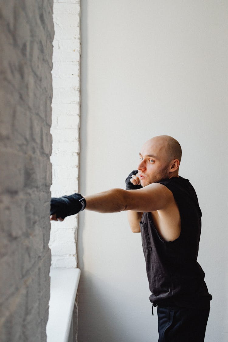 Man In Black Muscle Shirt With Hand Wraps Doing A Punch