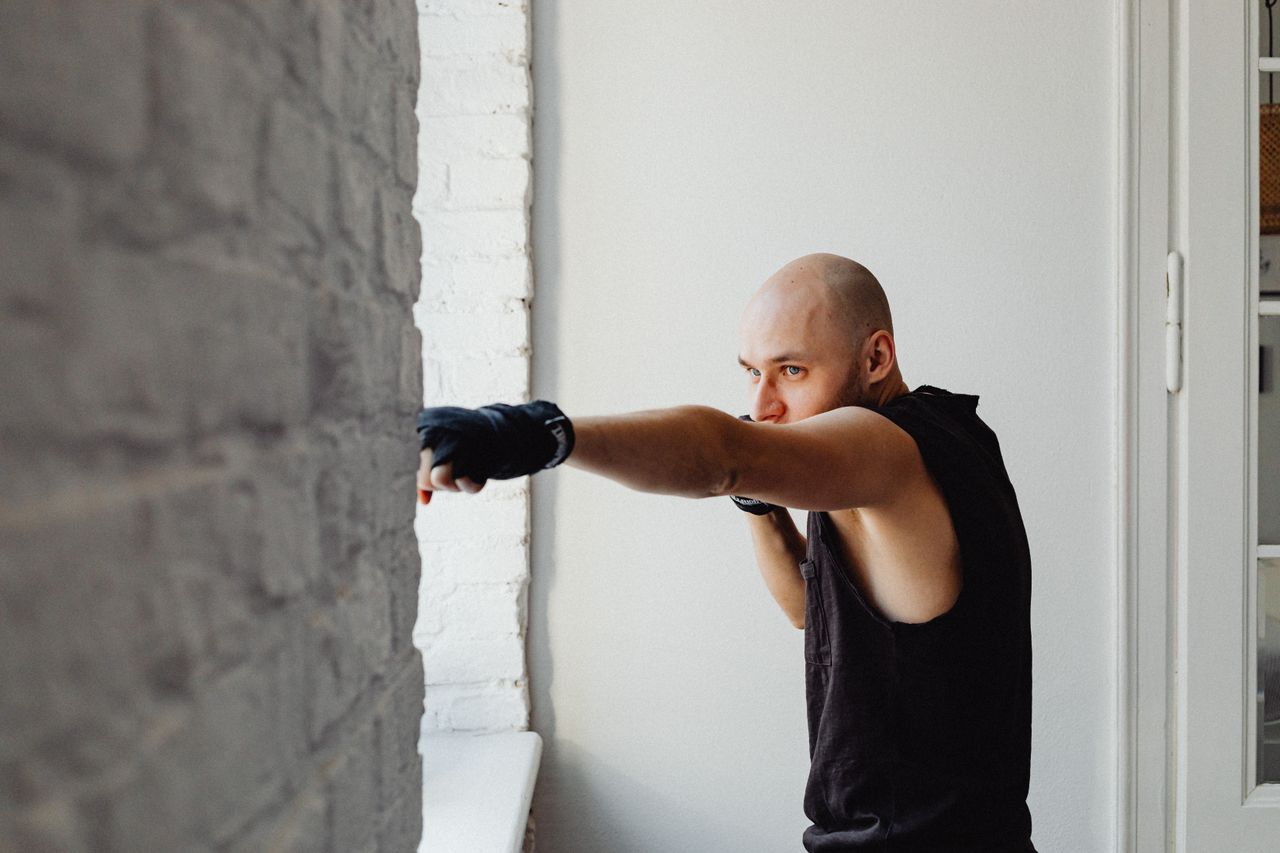 bald man working out indoors practicing boxing in a combat sport routi