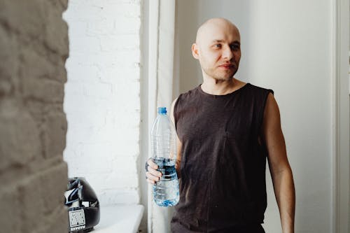 Free Man in Black Muscle Shirt Holding a Plastic Water Bottle Stock Photo