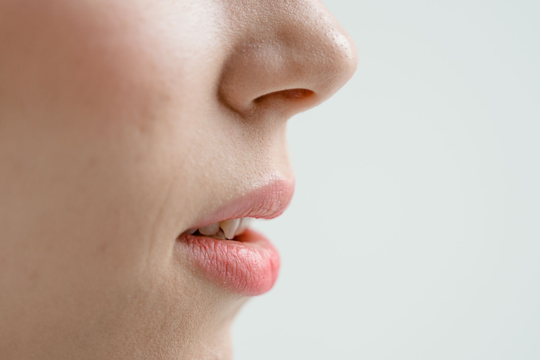 Detailed side view of a woman's nose and lips with natural skin texture. Perfect for beauty and skincare content.