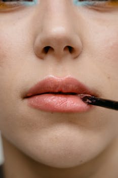 A detailed close-up image of a woman applying lipstick to her lips.