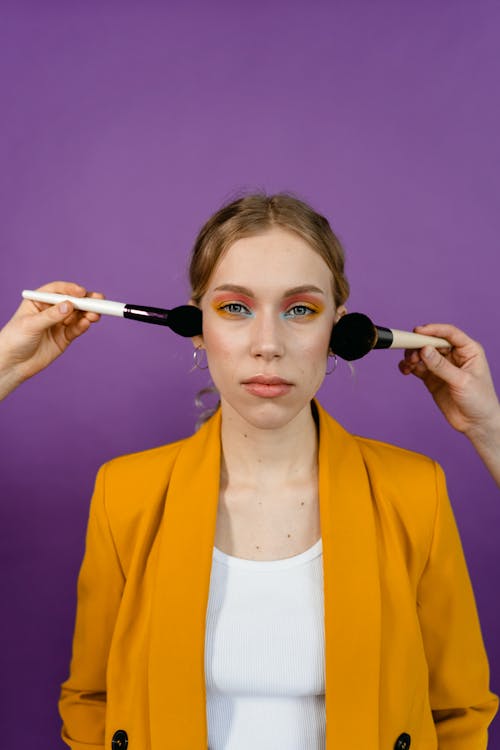 Woman in Orange Blazer with Eyeshadow and Blush On Being Applied