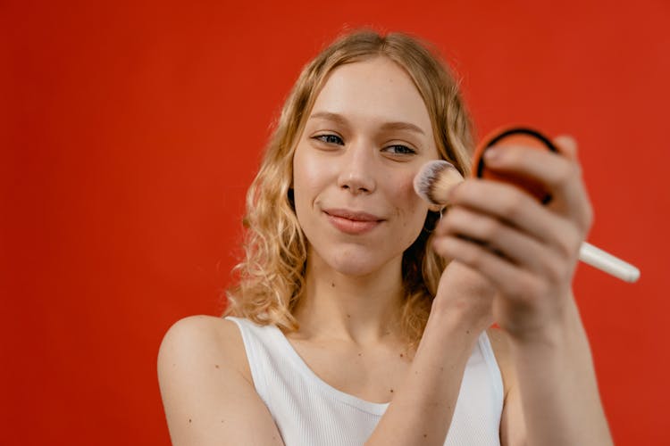 Woman In White Tank Top Applying A Concealer