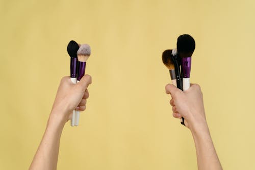 Person's Hands Holding Makeup Brushes