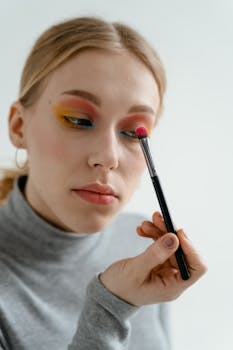 Close-up of a woman applying vibrant eyeshadow with a brush.