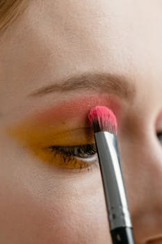 Vibrant eye makeup being applied with a brush, showcasing bold colors on eyelids.