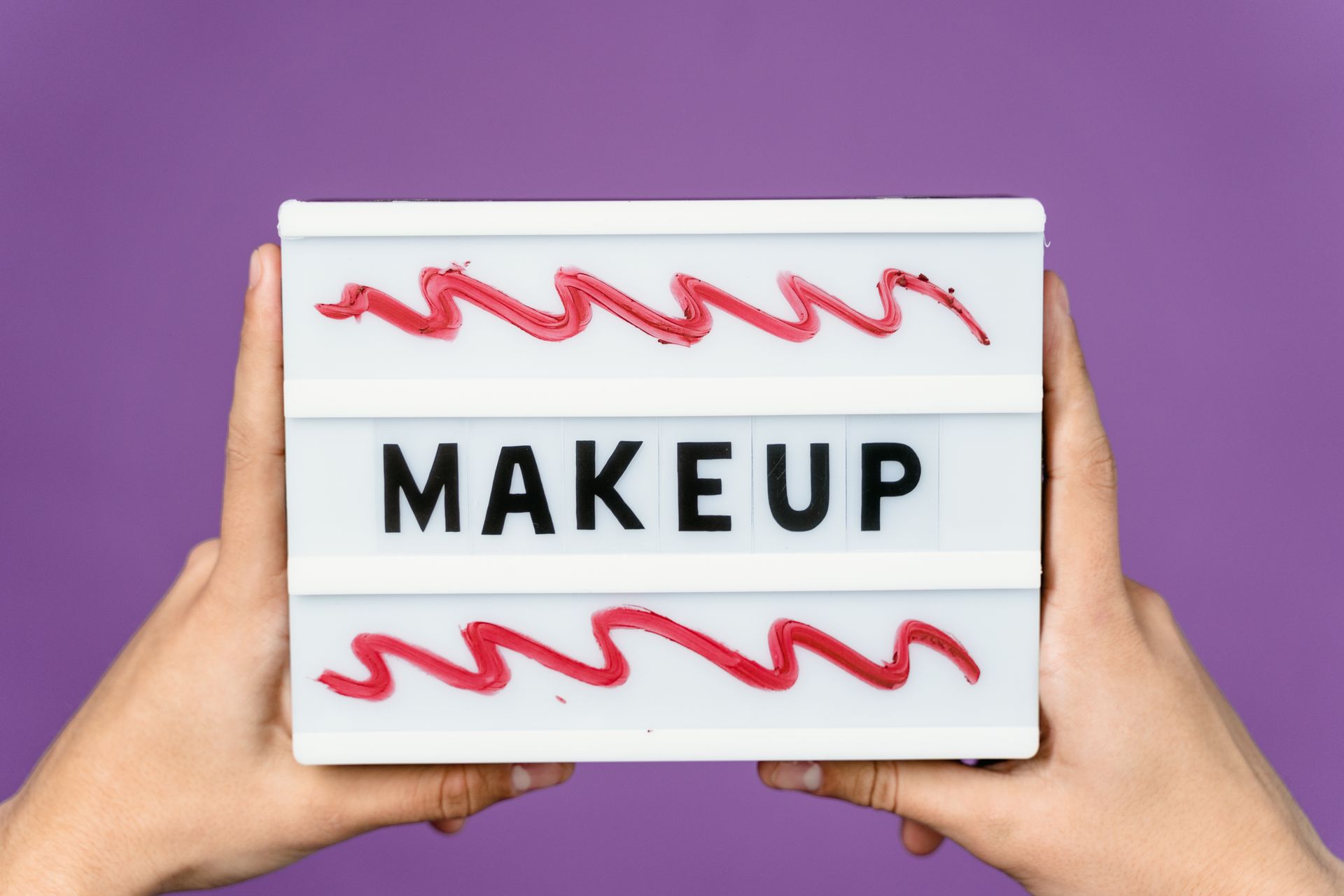 Person Holding a Sign with Makeup Text