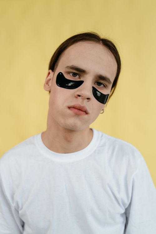 Free Portrait of a man wearing black under eye masks against a yellow background. Stock Photo