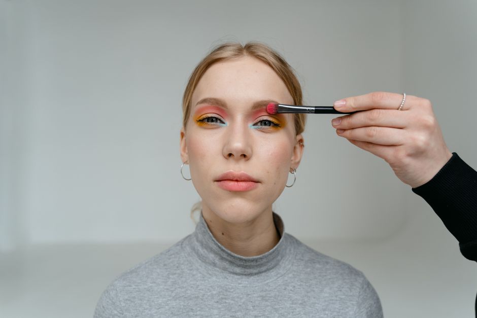 A person applying a DIY hair dye removal mixture to their hair, wearing protective gloves and using a tint brush.