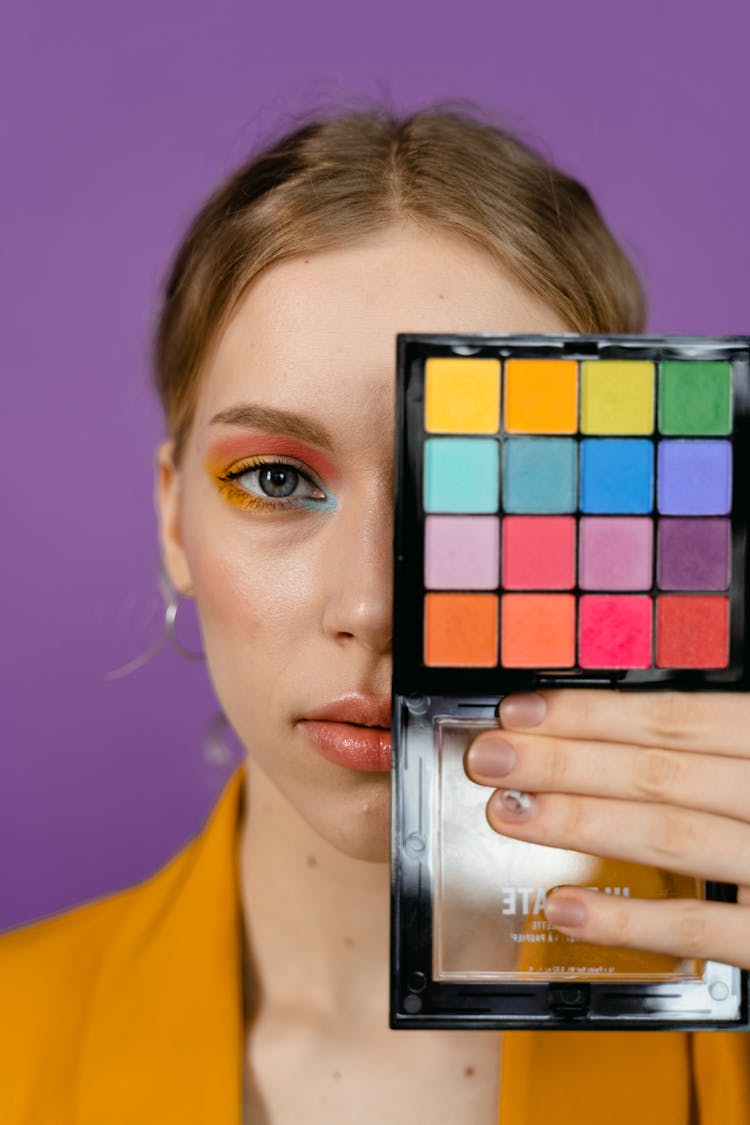 A Woman Covering Her Half Face With Eyeshadow Palette