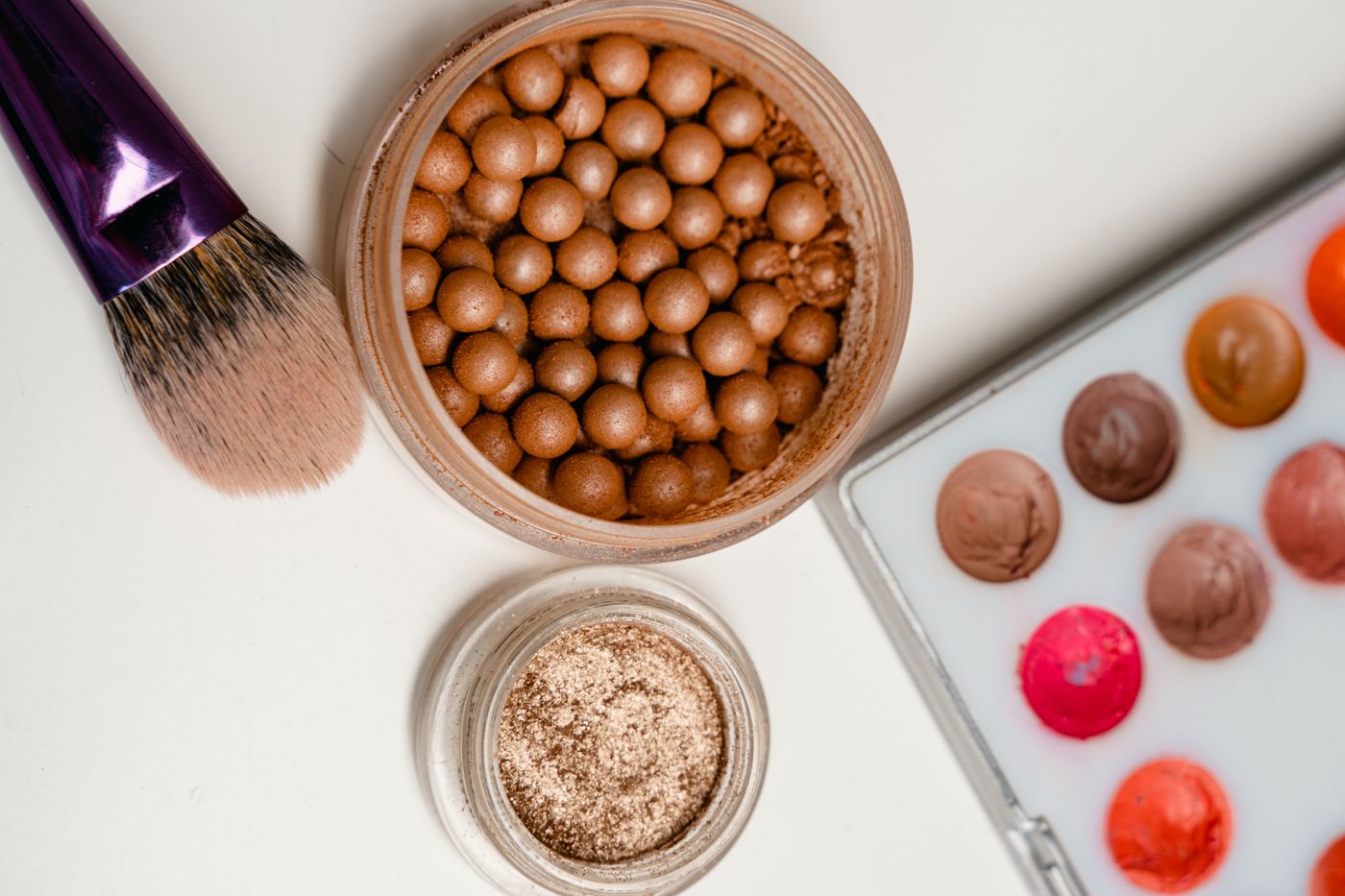 Makeup brushes palette and cosmetics arranged on white
