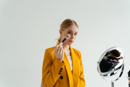 A Woman Looking at a Mirror while Applying Makeup