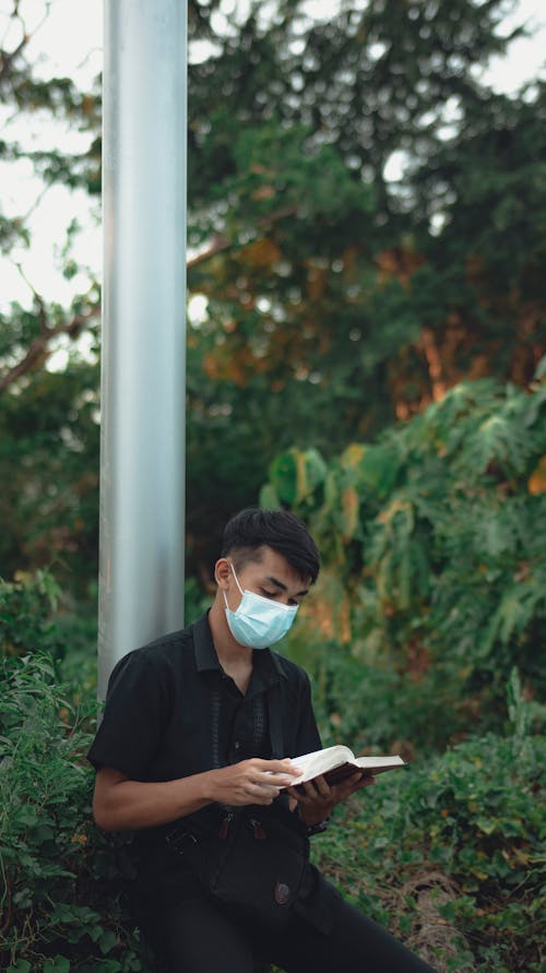 Free Man Wearing Face Mask Reading a Book Stock Photo
